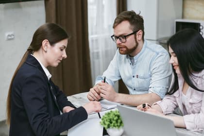 Agentă discutând cu doi clienți la biroul agenției