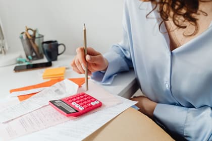 Asistentă de gestiune calculând cheltuielile pe baza chitanțelor, la birou