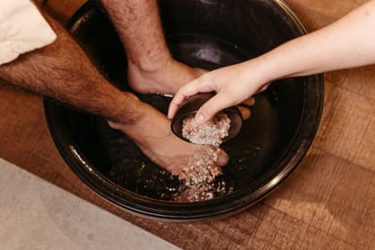 Băieș presărând sare într-o baie de picioare pregătită pentru un pacient
