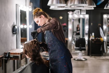 Coafeză vopsind părul unei cliente, într-un salon de coafură