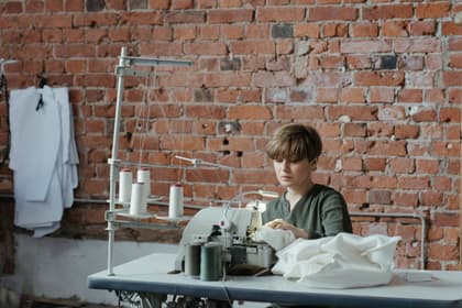 Confecționeră lucrând la o mașină de cusut industrială, într-un atelier de confecții
