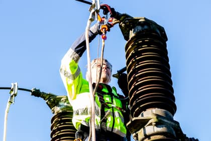 Electrician lucrând la izolatoarele unui separator de înaltă tensiune, într-o stație electrică