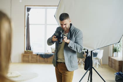 Fotograf verificând aparatul într-un studio, lângă un softbox