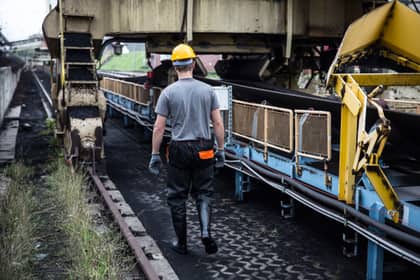 Inspector cu cască de protecție verificând o bandă transportoare, într-o instalație industrială