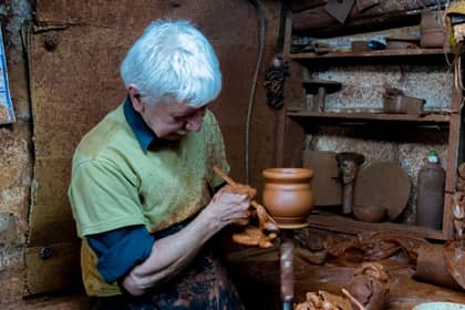 Olar finisând un vas de lut pe roata olarului, într-un atelier tradițional