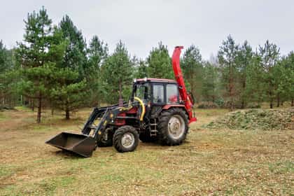 Tractor cu încărcător frontal și tocător de crăci, într-o poiană din pădure