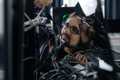 Tehnician IT printre cablurile de rețea din spatele unui calculator