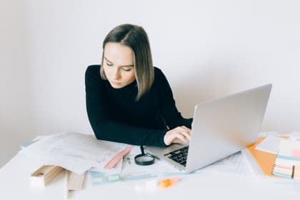 Operatoare introducând în laptop datele din documentele întinse pe birou