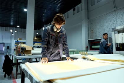 Specialist în calitate verificând foile de material pe masa de control, într-o fabrică