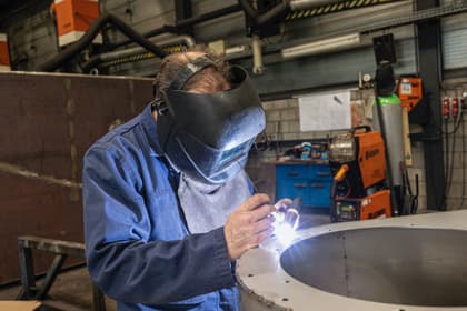 Sudor cu mască de protecție sudând o piesă de metal în atelier