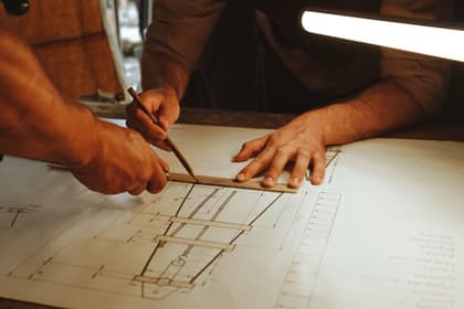 Mâini măsurând cu rigla pe planurile unui proiect de construcție
