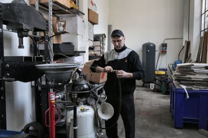 Tehnician reparând furtunul unui compresor într-un atelier de întreținere