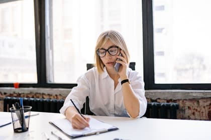 Funcționară notând o convorbire telefonică la biroul unui secretariat