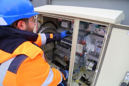 Tehnician electrician lucrând în tabloul de distribuție al unei instalații electrice