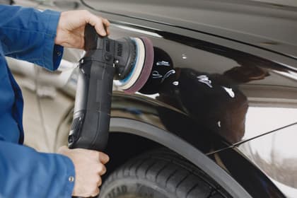 Vopsitor auto lustruind cu mașina orbitală caroseria unei mașini negre
