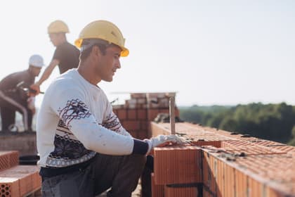 Zidar așezând blocuri ceramice pe stratul de mortar, la ridicarea unui perete
